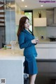 a woman in a blue suit standing in a kitchen