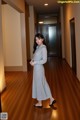 A woman standing in a long dress in a hallway.