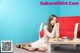 A woman sitting on a red couch next to a table.