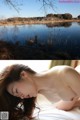 A naked woman laying on a bed next to a lake.