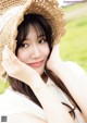 A woman wearing a straw hat in a field.