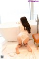 A woman in a white lingerie sitting in a bathtub.