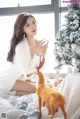 A woman sitting on a bed next to a christmas tree.