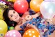 A woman laying on top of a pile of balloons.