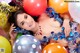 A woman laying on top of a pile of balloons.