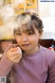 A young girl eating a piece of food with a spoon.