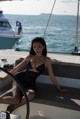 A woman in a black bathing suit sitting on a boat.