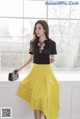 A woman in a black top and yellow skirt posing for a picture.