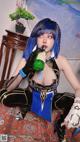 A woman with blue hair is holding a bottle of beer.