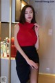 A woman in a red top and black skirt posing for a picture.