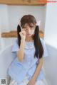 A young girl sitting in a bathtub wearing a blue shirt and white skirt.