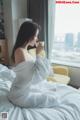 A woman sitting on a bed holding a cup of coffee.