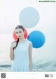 A woman in a white dress holding a bunch of balloons.