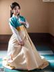 A woman in a blue and white hanbok is posing for a picture.