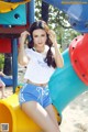 A woman in a white shirt and blue shorts posing on a slide.